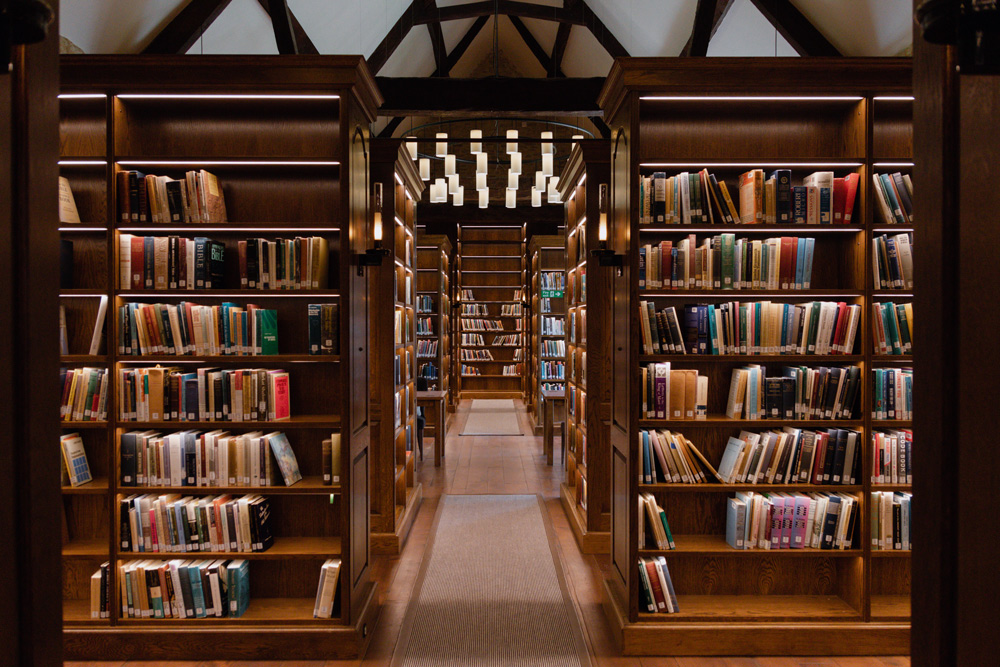 Wide view of library shelves with books, LED lighting and large chandeliers hanging from ceiling