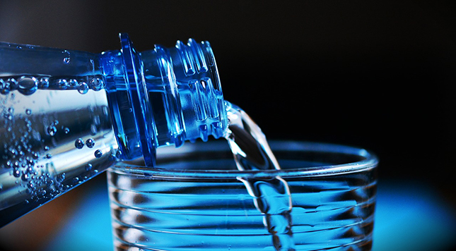 Water bottle pouring into glass - reducing our plastic consumption